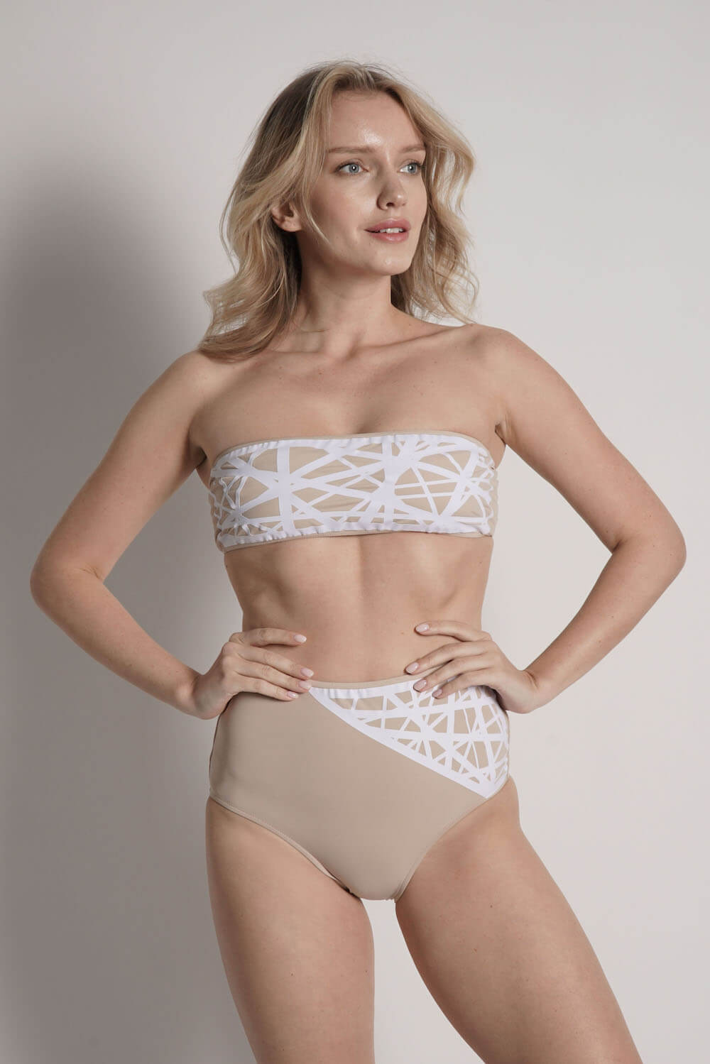 Model wears Lillian bandeau bikini top in camel with white laser details