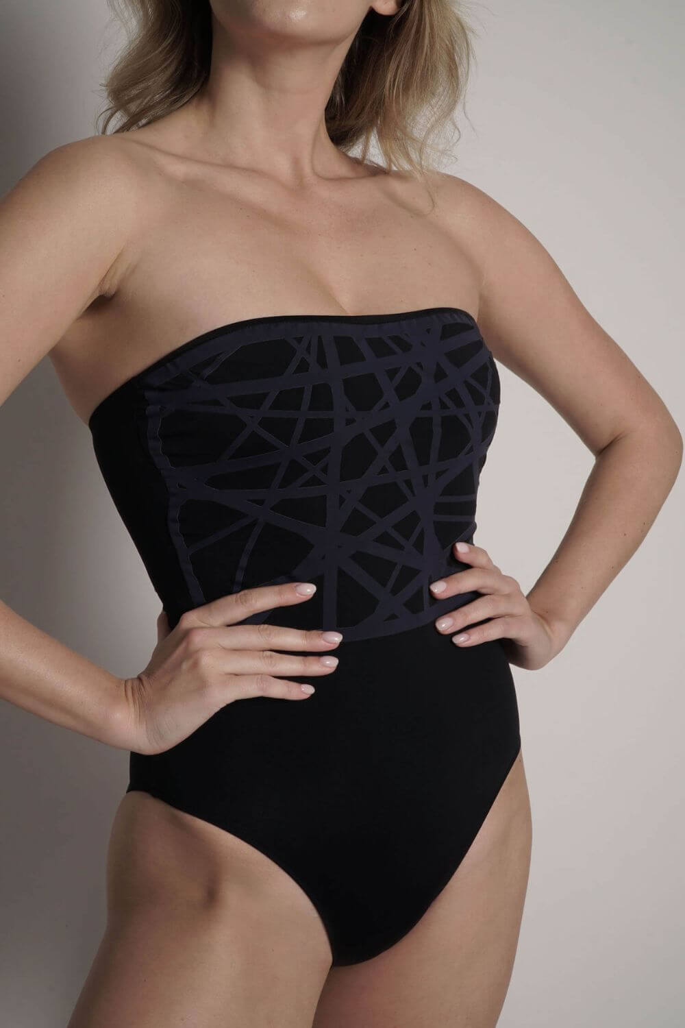Close image of the navy blue laser-cut detail applied to the Angela strapless one piece swimsuit black.
