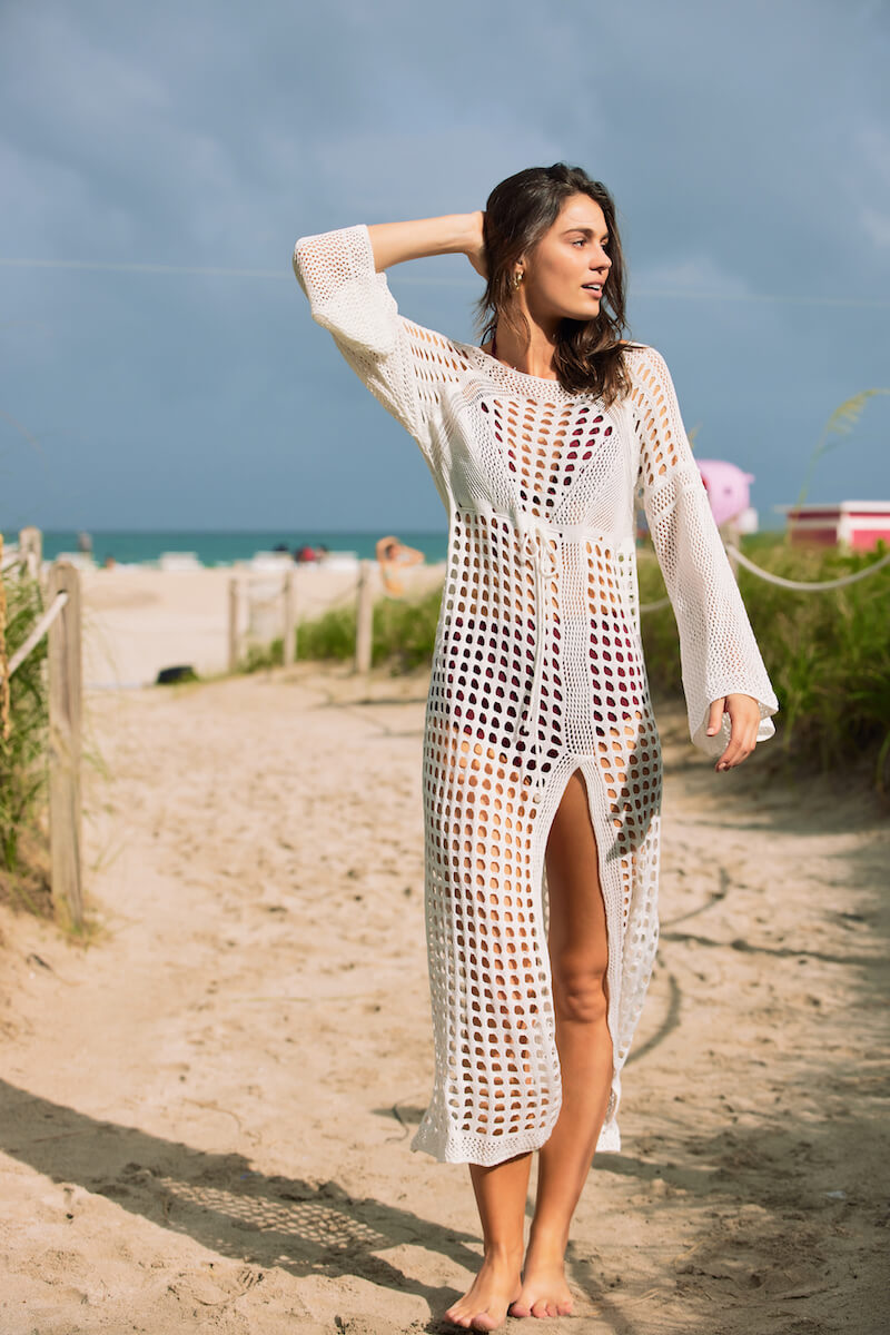 Model at the beach wearing the Stella white crochet cover up